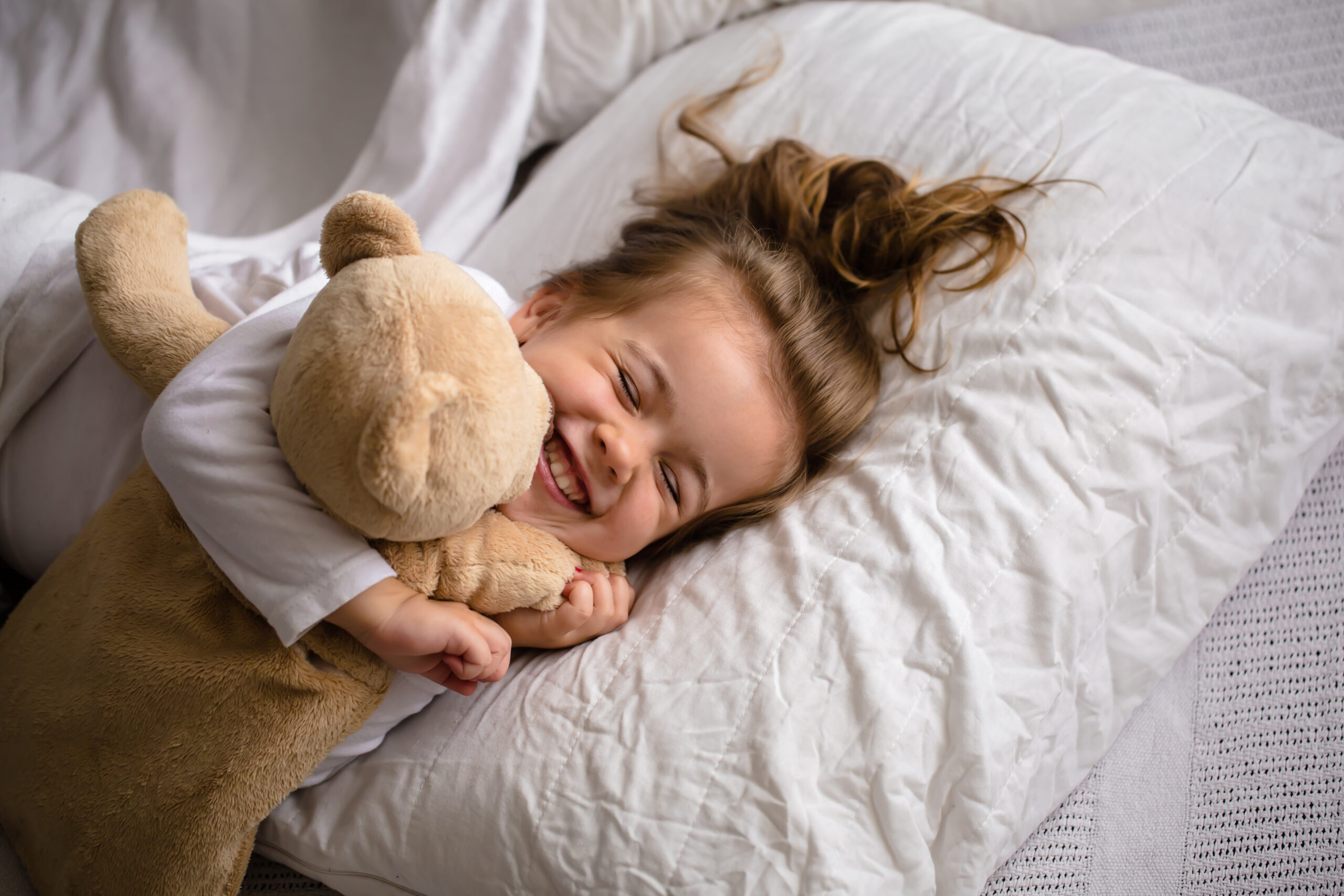 little girl in bed with soft toy the emotions of a child, white bed